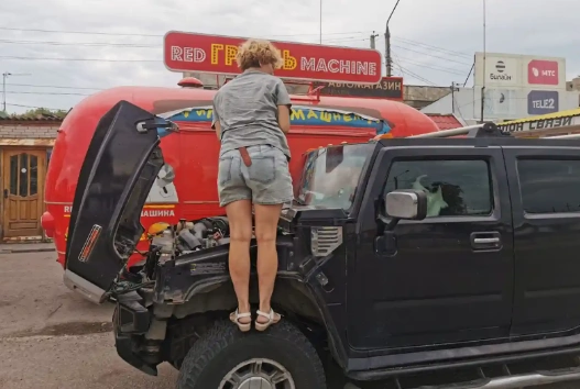 Женщина стоит на колесе Хаммер, и заглядывает в двигатель